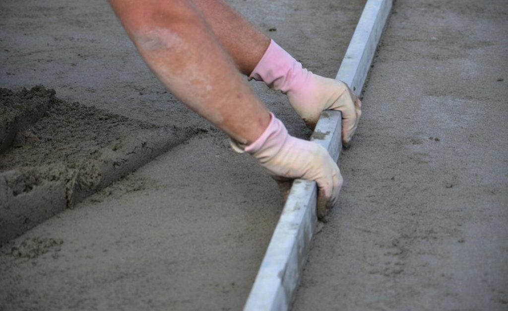 A Picture Of A Concrete Worker Smoothing Out Concrete Before Troweling It out With A Metal Screed. Concrete Contractors In Delaware County Pa